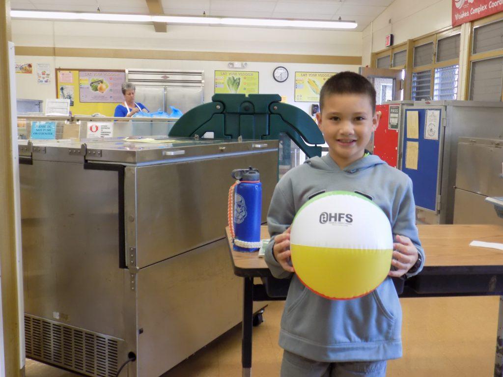 child poses with an HFS beach ball