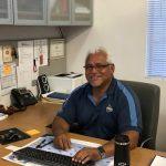 a man sitting at his desk smiling for a photo. 