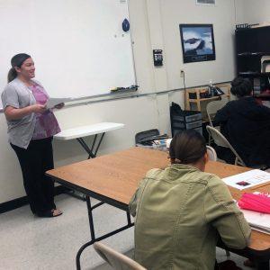 HFS staff member standing in the front of a classroom speaking to a few students