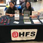 two staff members sitting at a table smiling