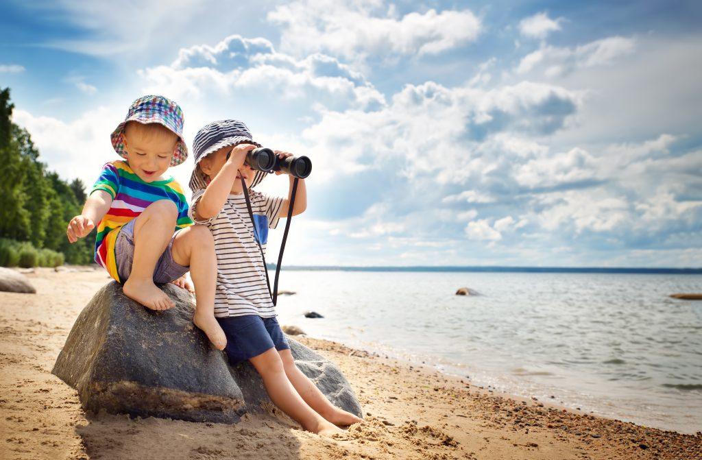 Babygirl and babyboy sitting on the beach in summer hats