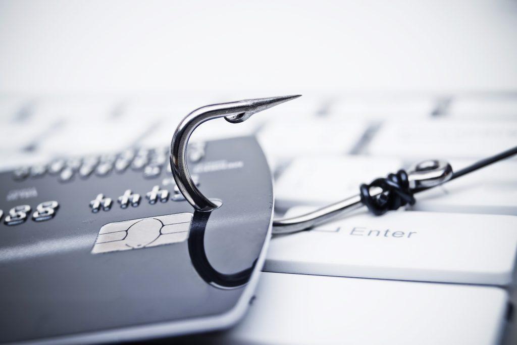 piles of credit cards with a fish hook on computer keyboard