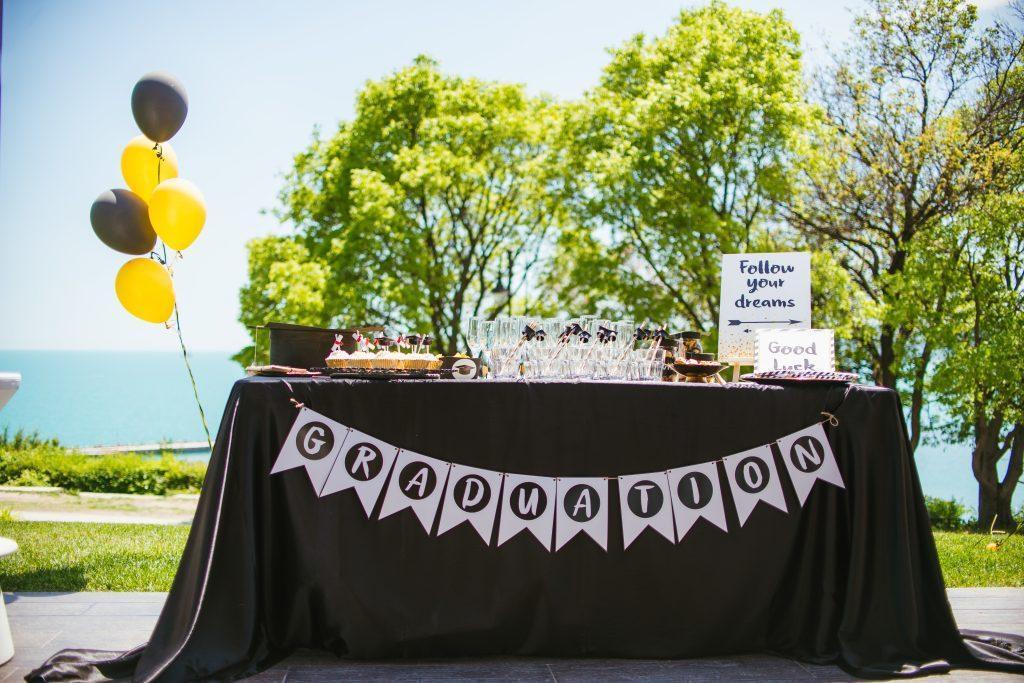 table set up at a graduation party - black tablecloth with graduation banner and yellow and black balloons