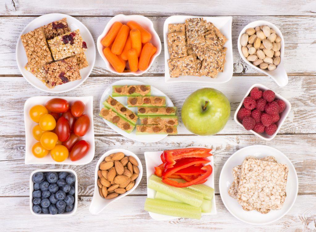 a medley of colorful healthy snacks laid out in separate plates on a wooden table. Top view