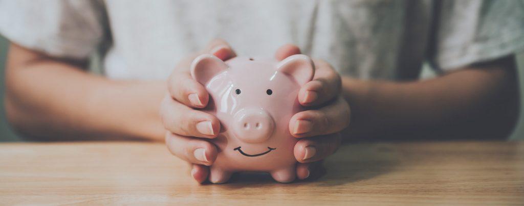 man holding piggy bank on wooden table