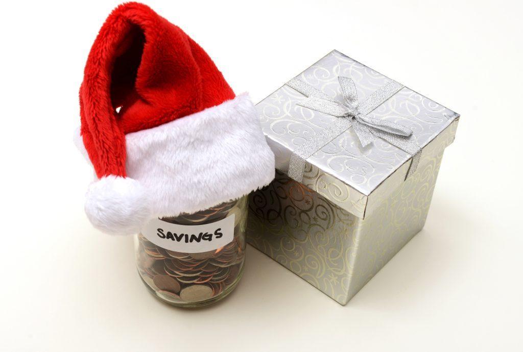 christmas present next to a jar of coins with a santa hat