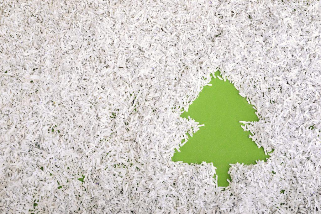heap of shredded paper forms a symbol of a green fir tree to the right of the image