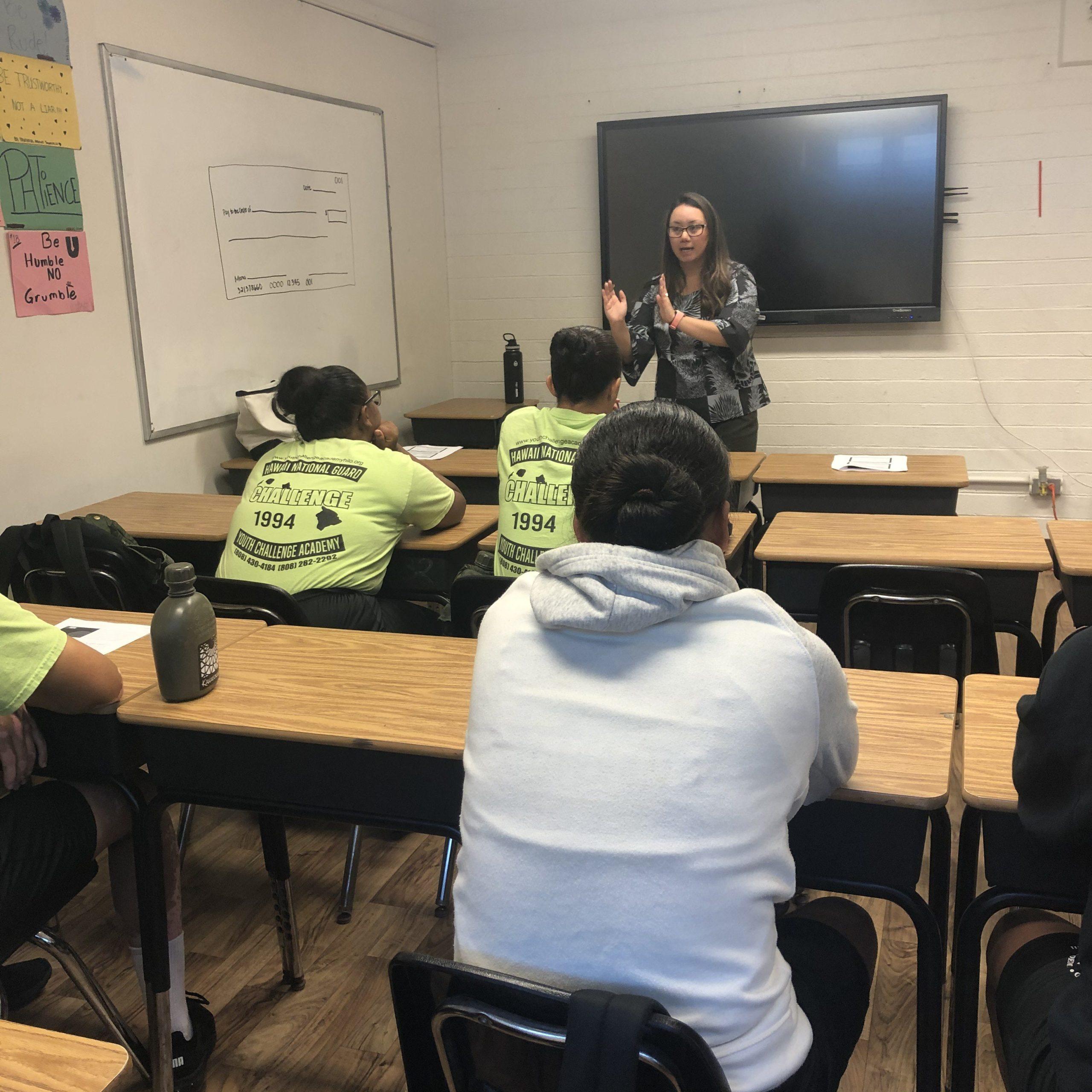 an HFS staff member stands at the front of the classroom delivering a presentation to a group of youth challenge cadets